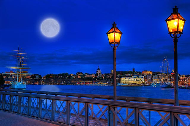 A full moon rises over the skyline of Södermalm as seen from the Citadel Islet Bridge